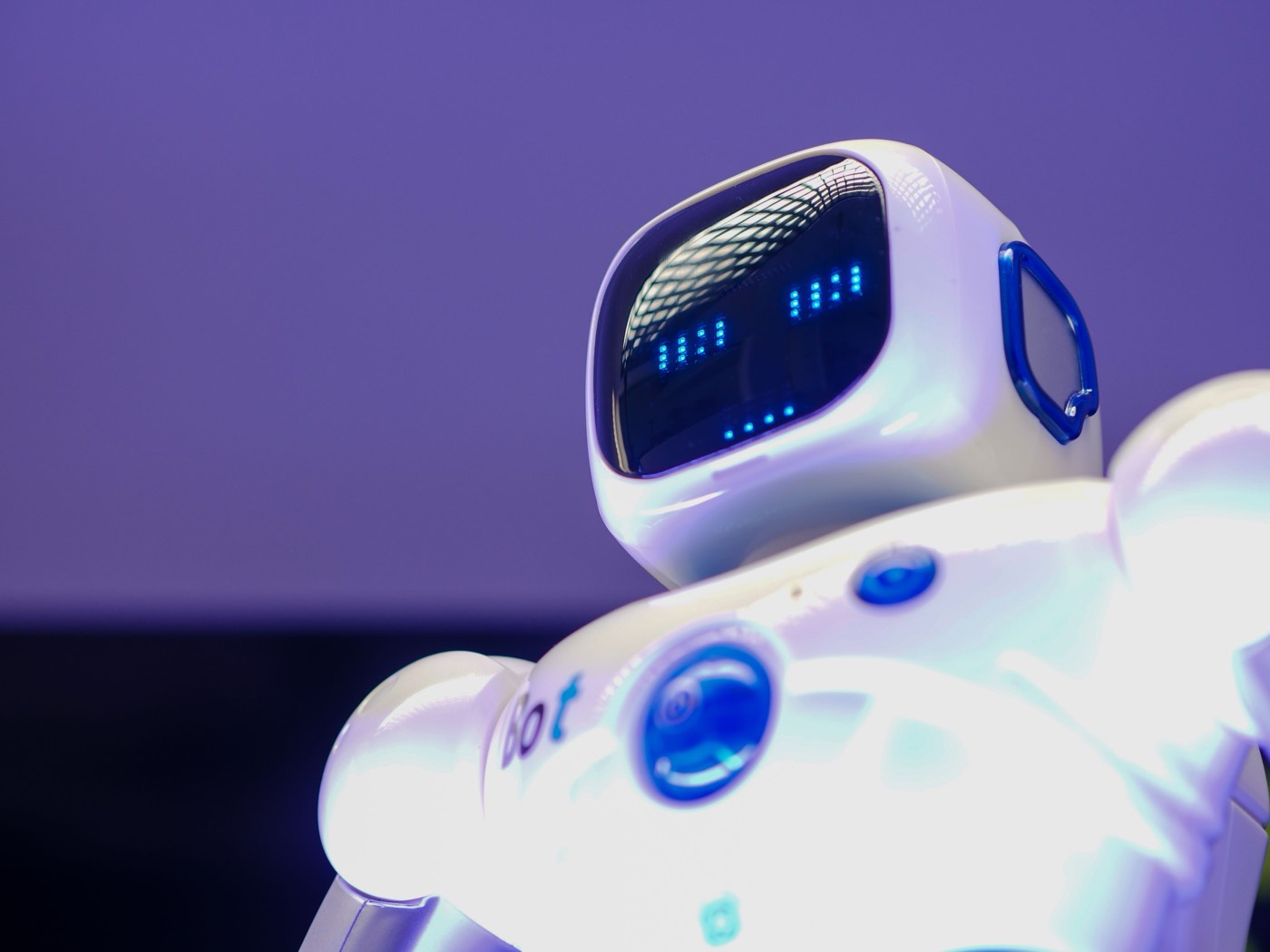 A small white robot with a glowing face display