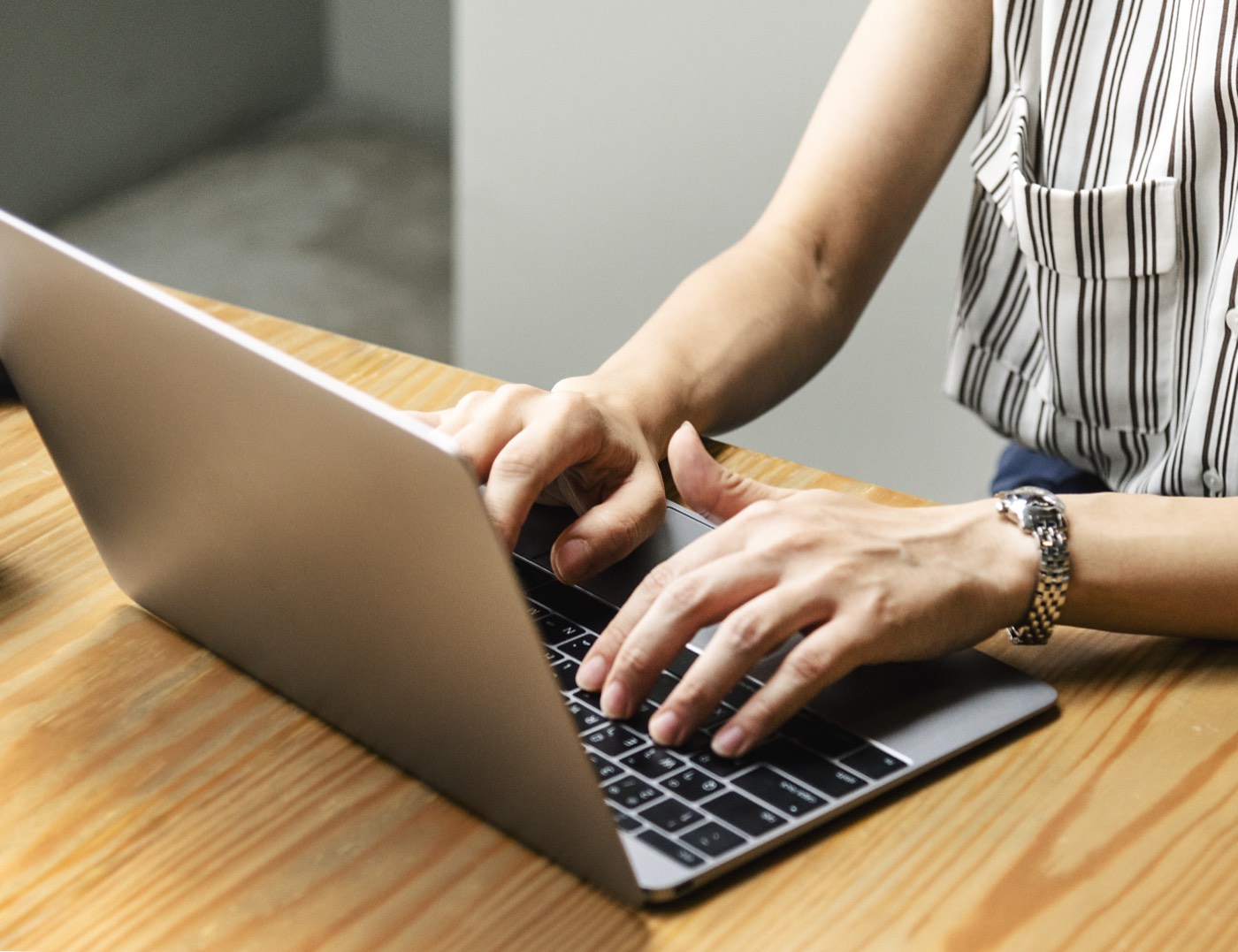 Hands typing on a laptop at a wooden desk